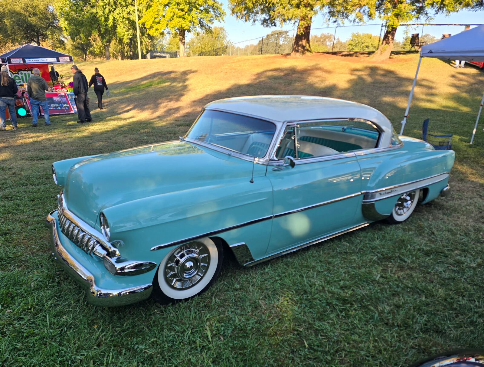 Turquoise and white classic hardtop parked on the grass at Rusch Park