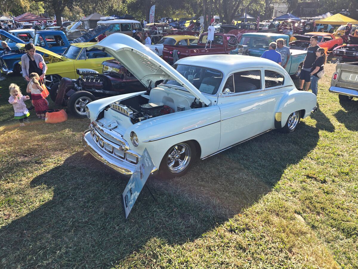 White classic Chevrolet with its hood open on the show field