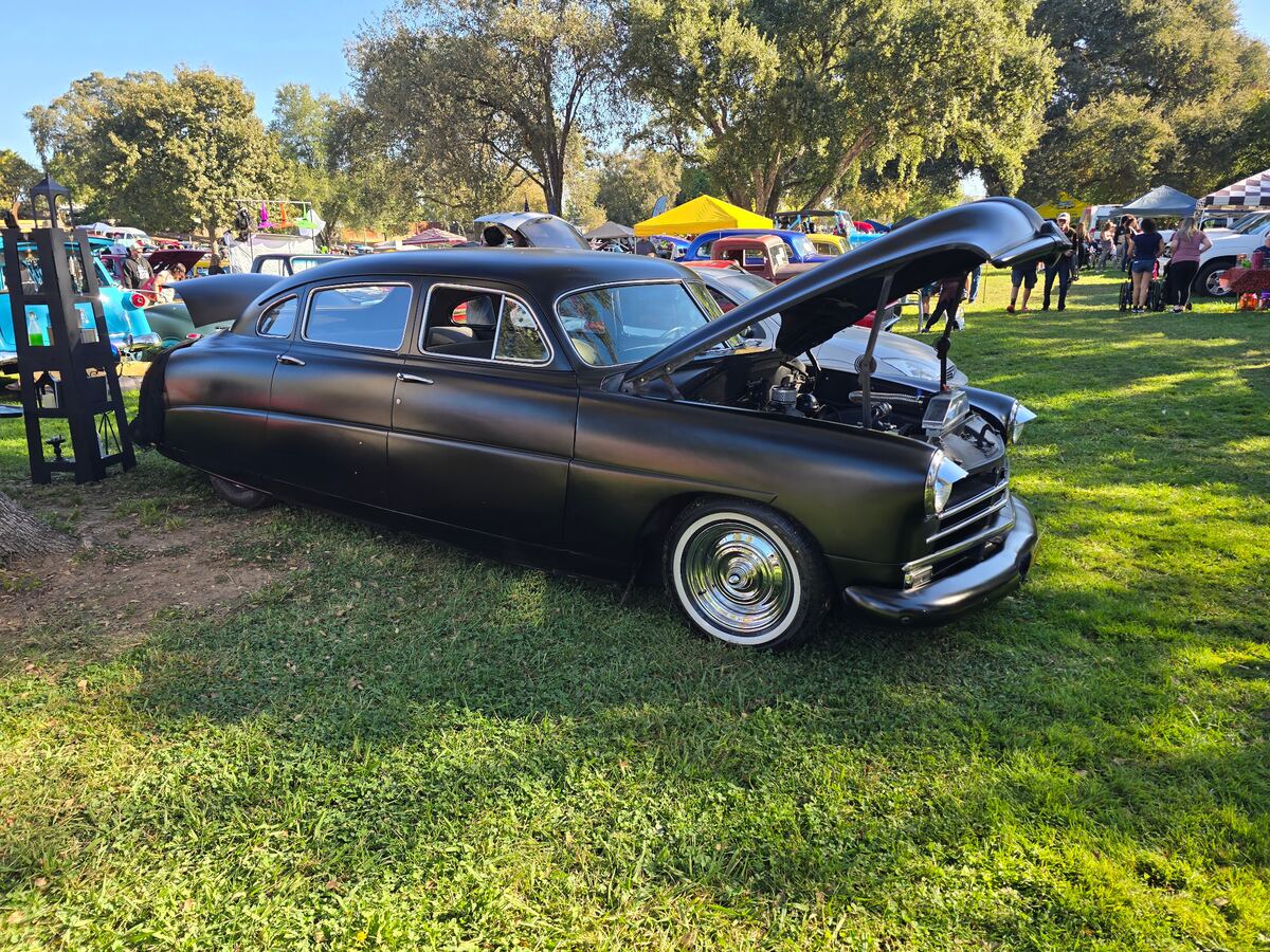 Dark custom coupe with its hood open and whitewall tires