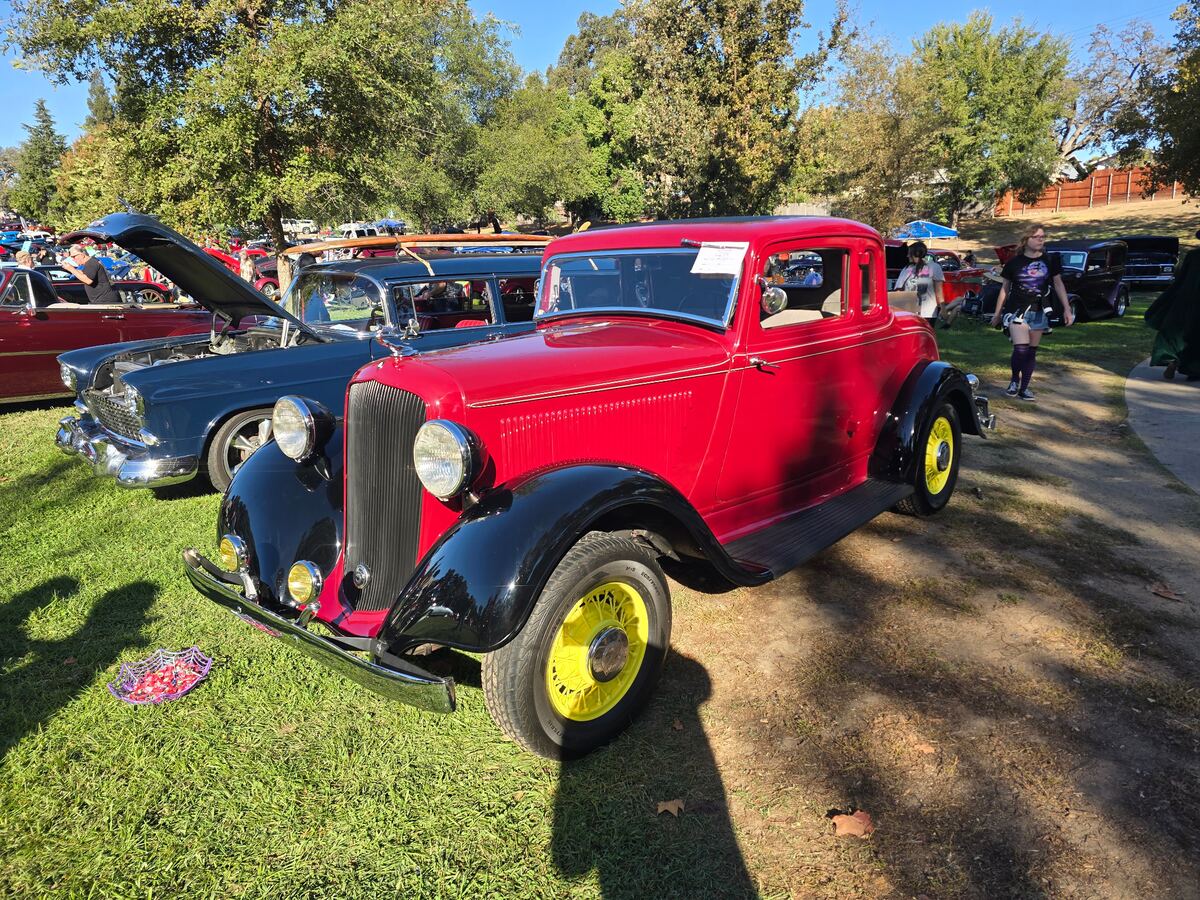 Red early Ford coupe with yellow wheels beside the show field
