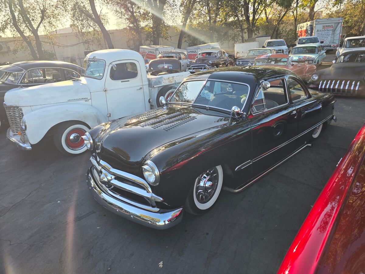 Black convertible among the cars in late-afternoon light